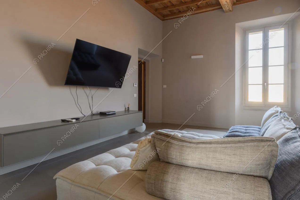 Luminoso salotto con soffitto a cassettoni, divano angolare e pareti bianche