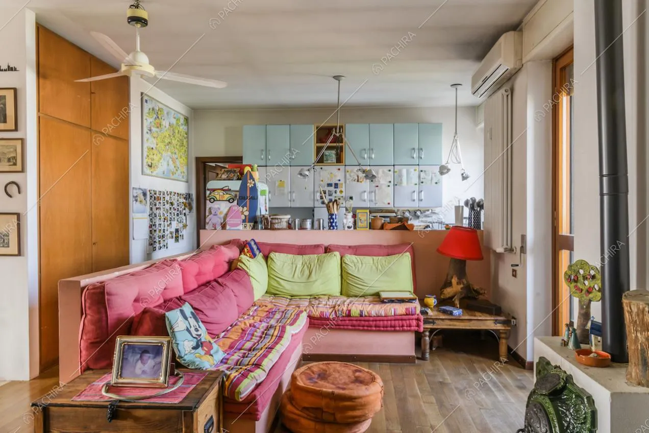 Salotto con divano, cucina a vista e pavimento in parquet