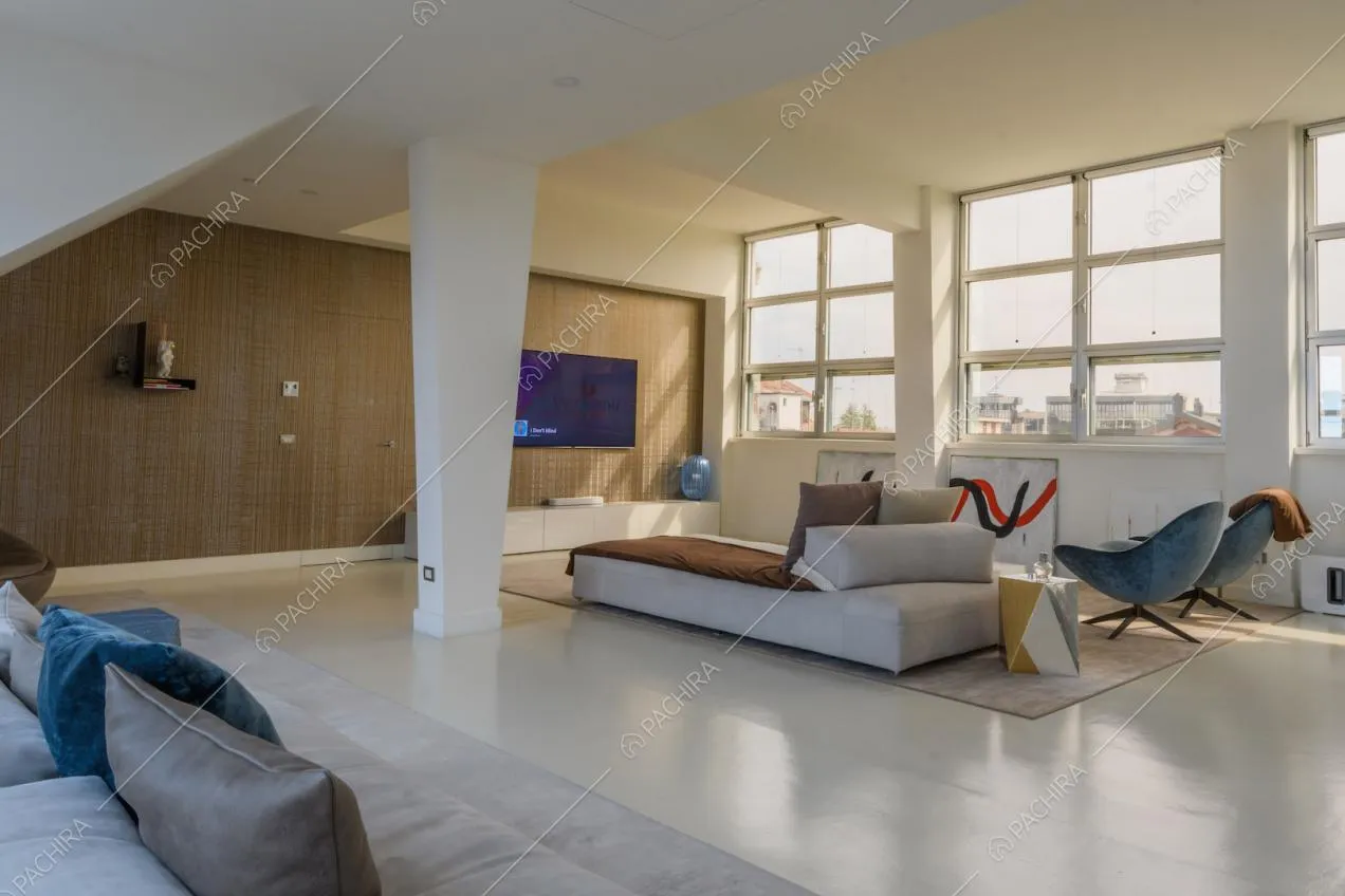 Luminosa zona living con due divani, parete marrone e pavimento in resina bianco