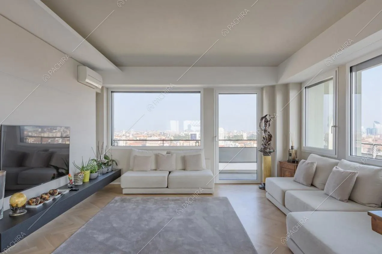 Pavimento in parquet a spina di pesce nella zona living con vetrate e vista sullo skyline