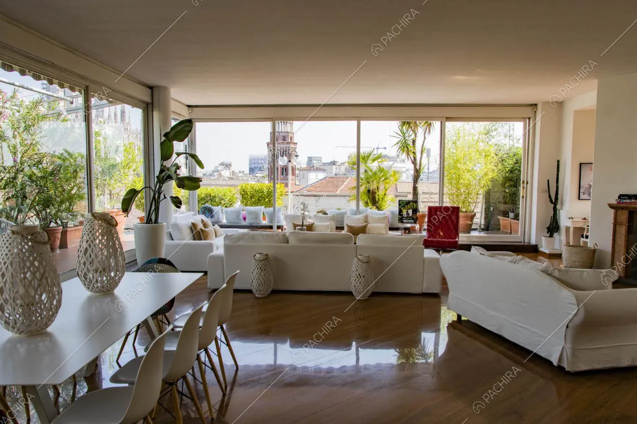 Divani bianchi nella luminosa zona living con grandi vetrate e pavimento in parquet