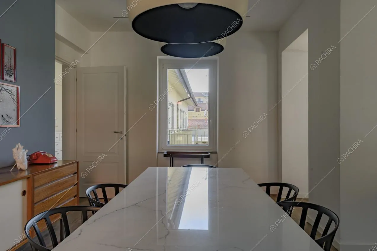 Zona pranzo con tavolo in marmo bianco e sedie nere