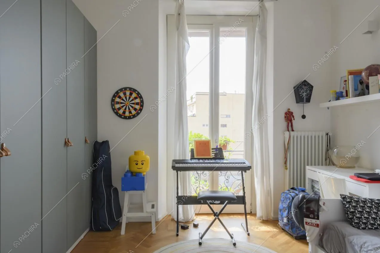 Armadio grigio, pianola e porta finestra nella camera da letto