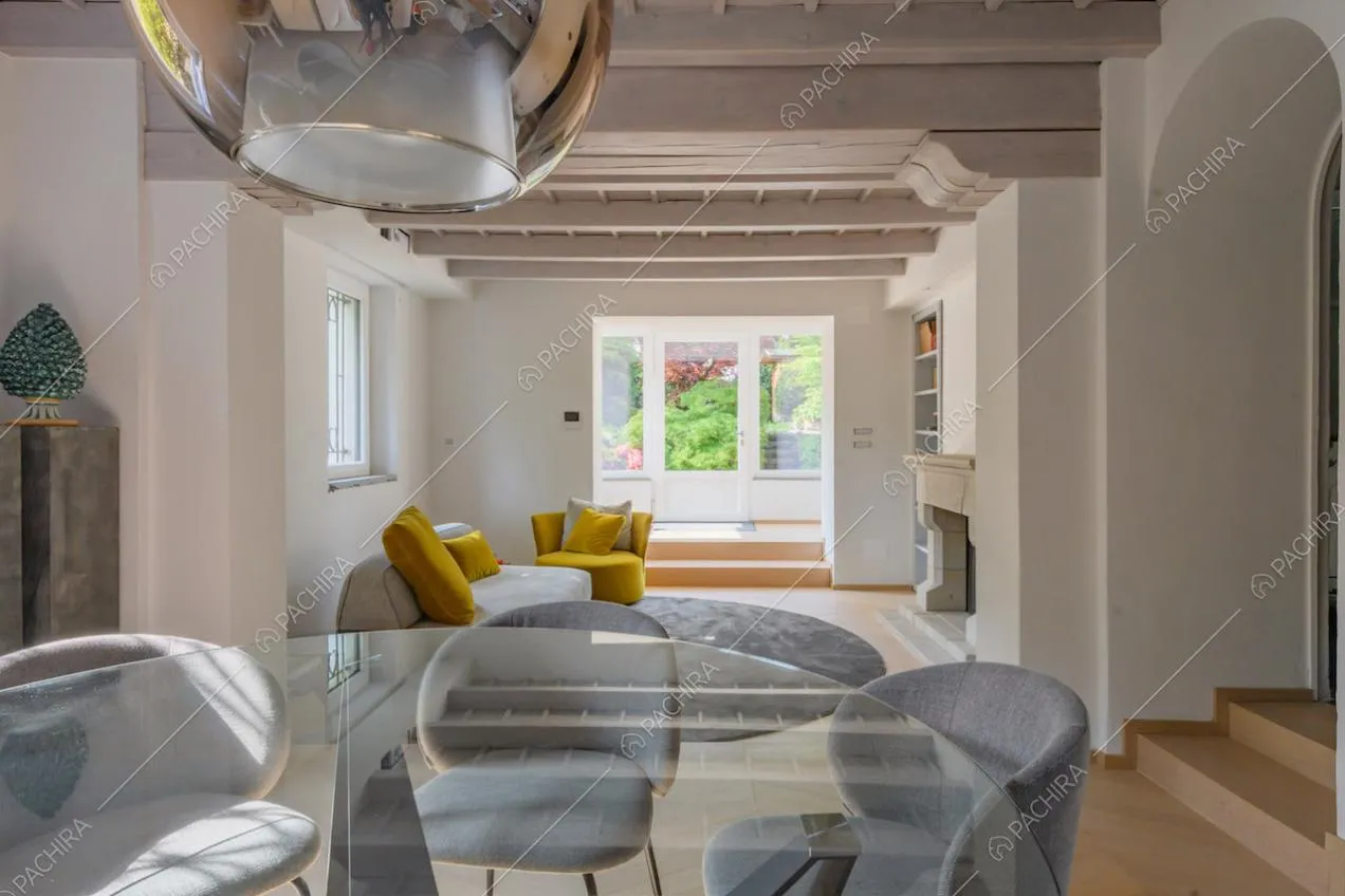 Tavolo da pranzo e sedie grigie nel salotto con pavimento in parquet e camino