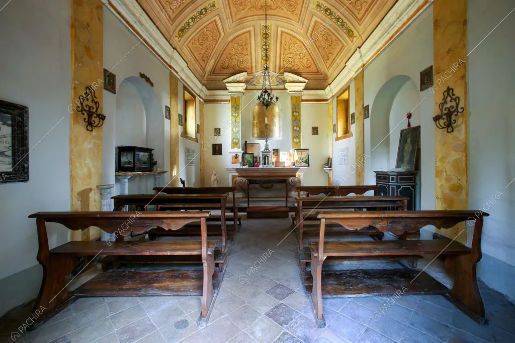 Cappella privata con panche in legno e soffitto affrescato con nuances gialle