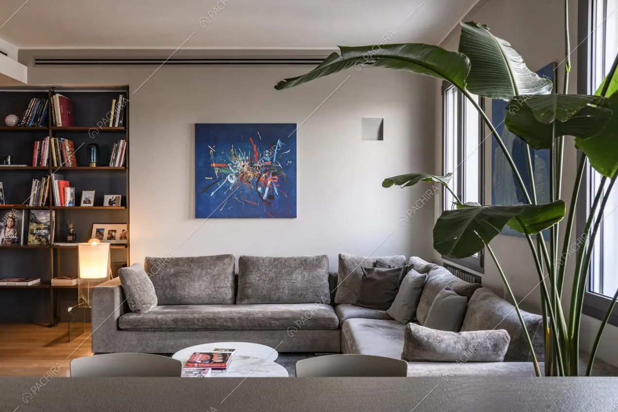 Divano in velluto grigio, libreria e quadro sulla parete