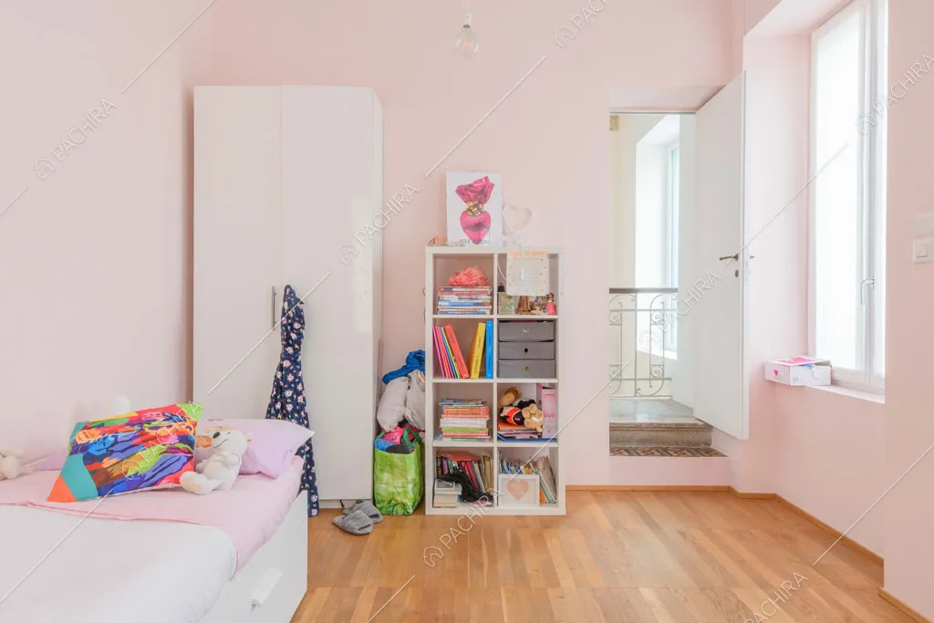 Pareti rosa nella cameretta con letto singolo e pavimento in parquet