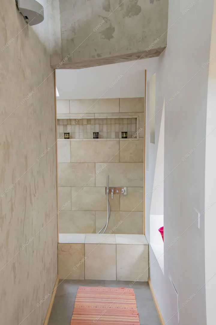 Corridoio che conduce al bagno con vasca e parete in lastre di pietra