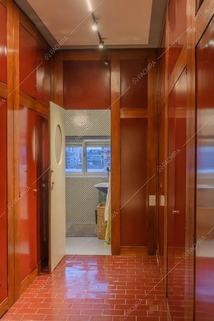 Corridoio con pareti rosse e in legno, piastrelle lucide e vista sul bagno