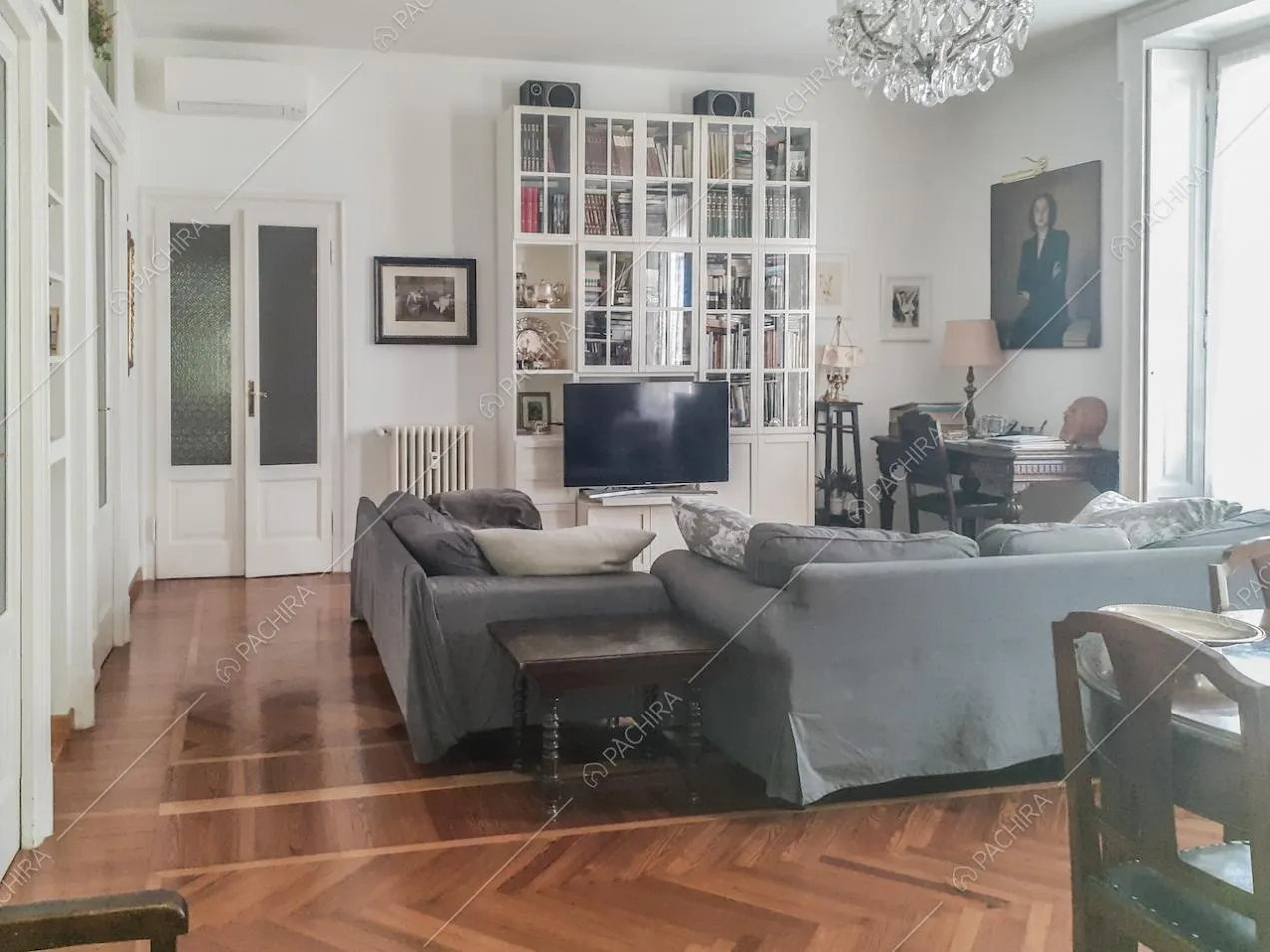 Libreria con ante in vetro, televisore e scrivania antica