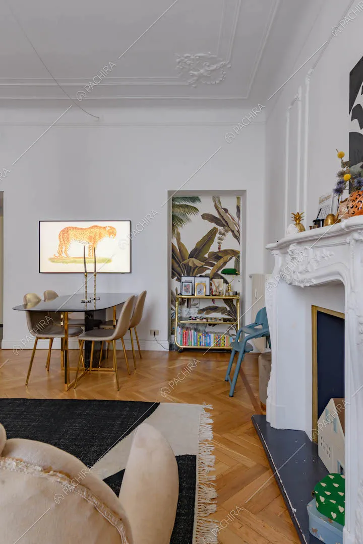 Divano accanto al camino, pavimento in parquet a spina di pesce e boiserie sul soffitto