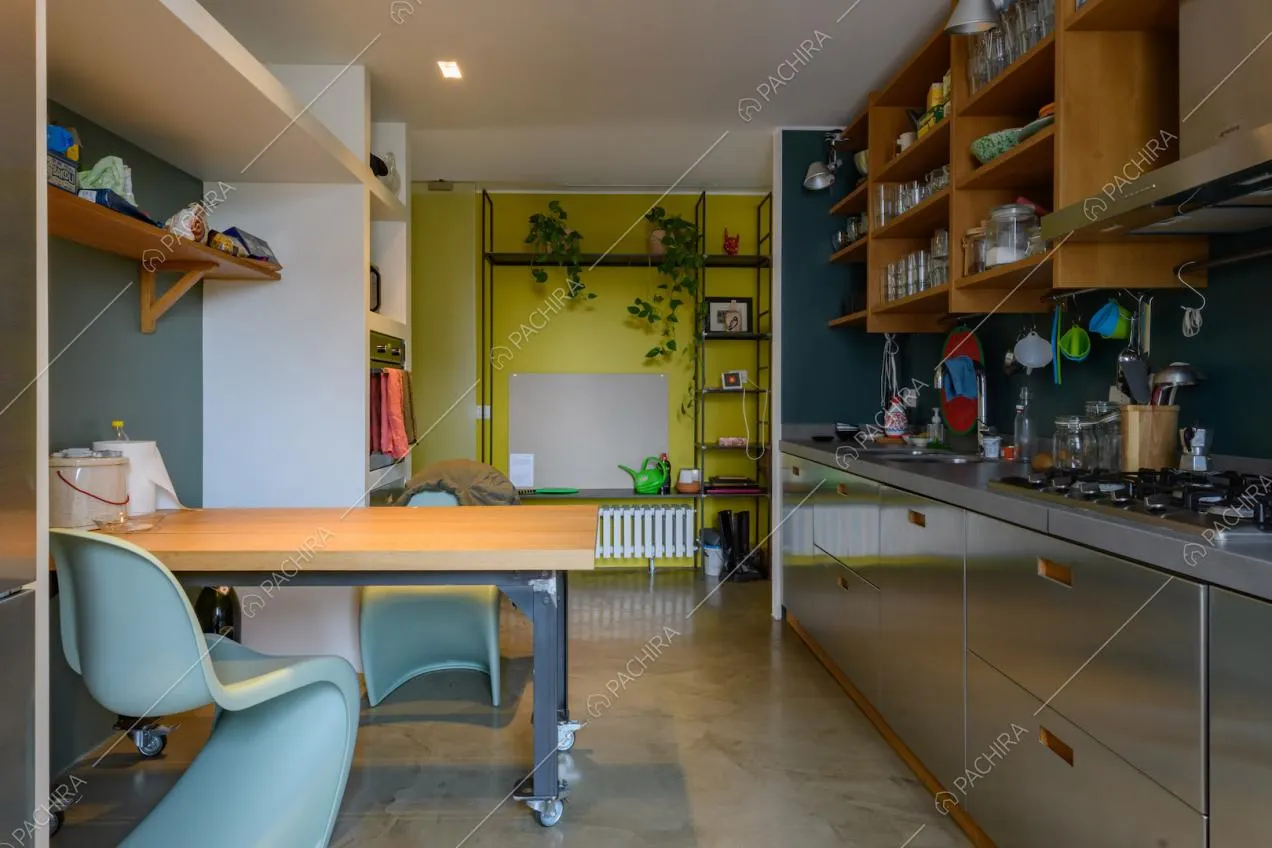 Tavolo in legno con rotelle nella cucina a parete in acciaio e con fornelli a gas