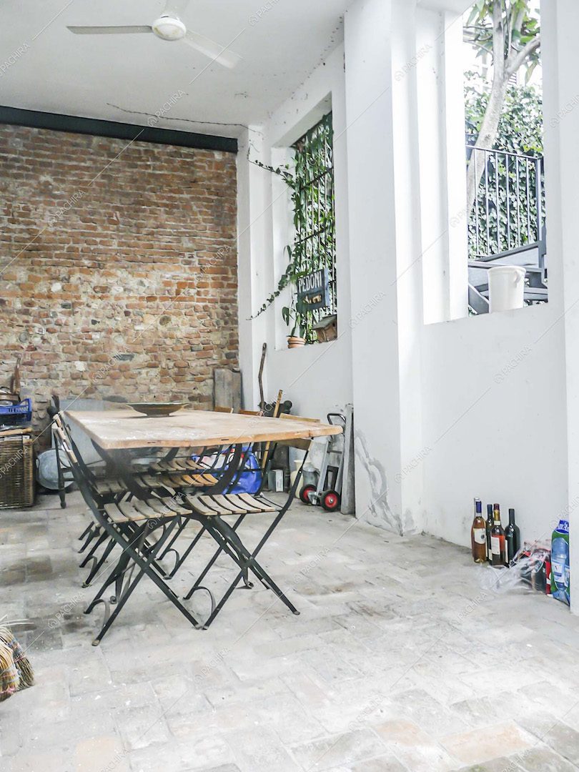 Sala da pranzo con parete in mattoni rossi a vista, tavolo in legno e pavimento in pietra