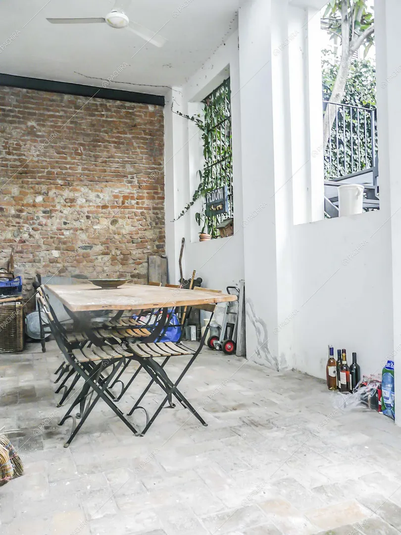 Sala da pranzo con parete in mattoni rossi a vista, tavolo in legno e pavimento in pietra