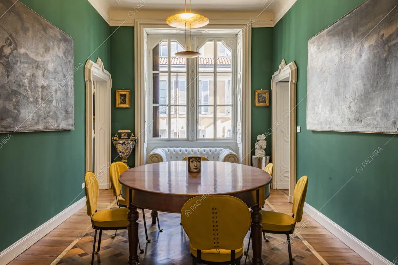 Sala da pranzo con pareti verdi e quadri in bianco e nero