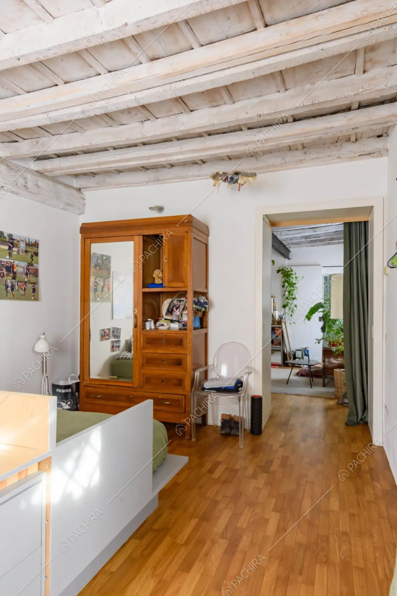 Camera da letto con pavimento in parquet e tenda verde che la separa dalla cucina