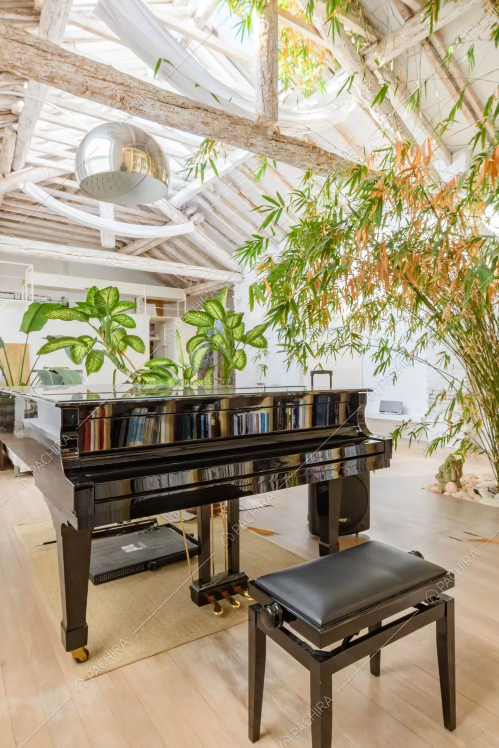 Pianoforte nero nella luminosa zona living con pavimento in parquet e soffitto con travi a vista