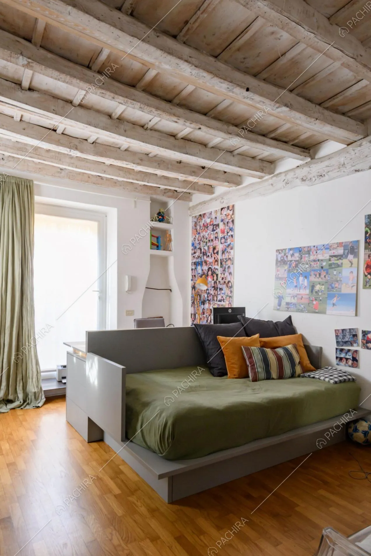 Luminosa camera da letto con pareti bianche, pavimento in parquet e travi a vista