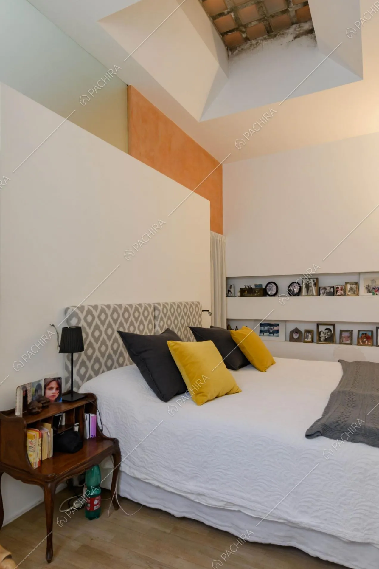 Camera da letto matrimoniale con pareti bianche, lucernario chiuso e pavimento in parquet