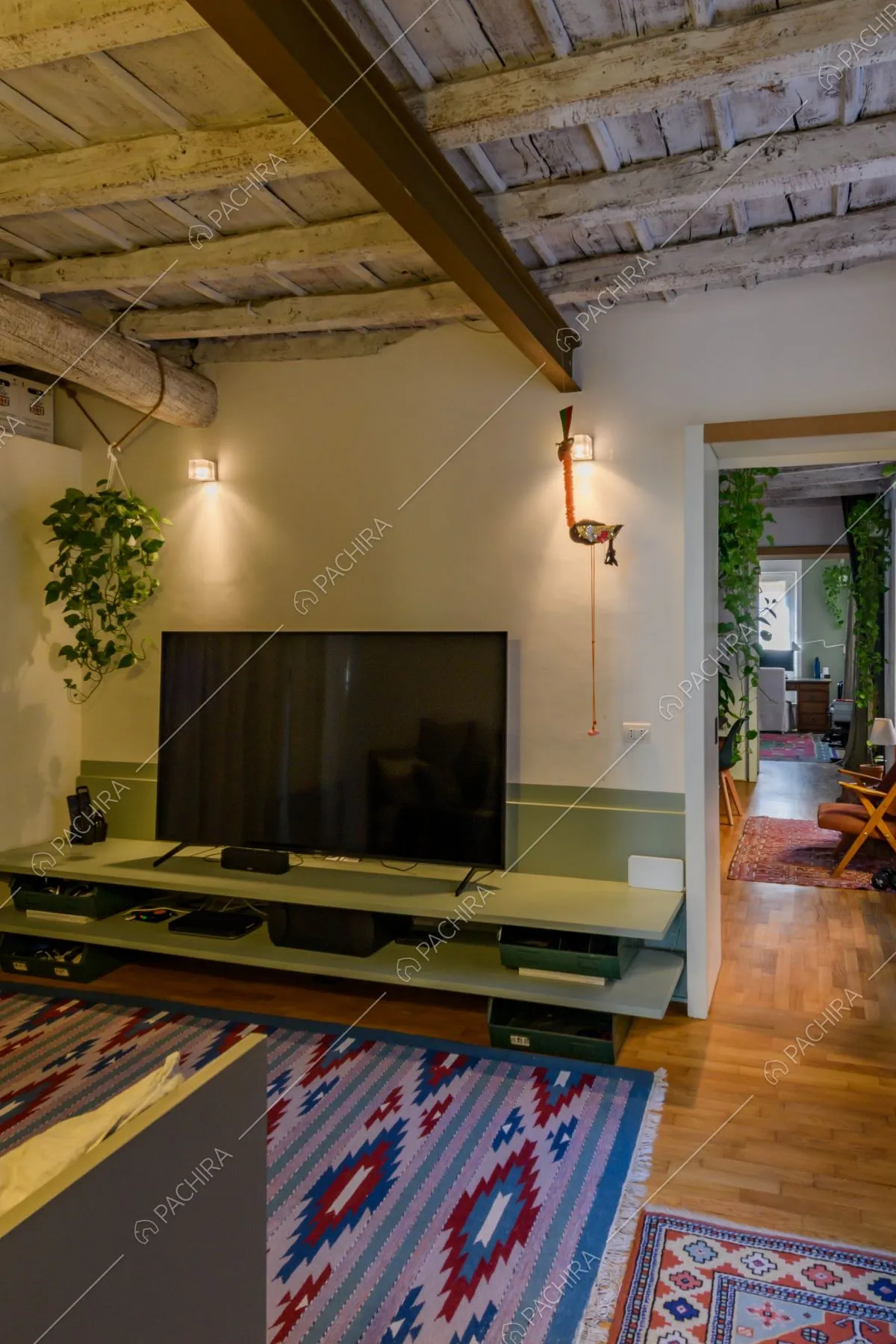 Salotto con divani, televisione, pareti bianche e corridoio che conduce allo studio
