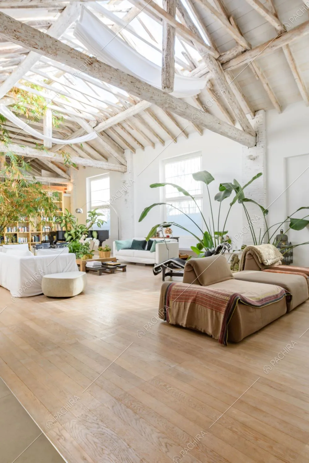 Ampio salotto con pavimento in parquet, divani marroni e bianchi e travi a vista