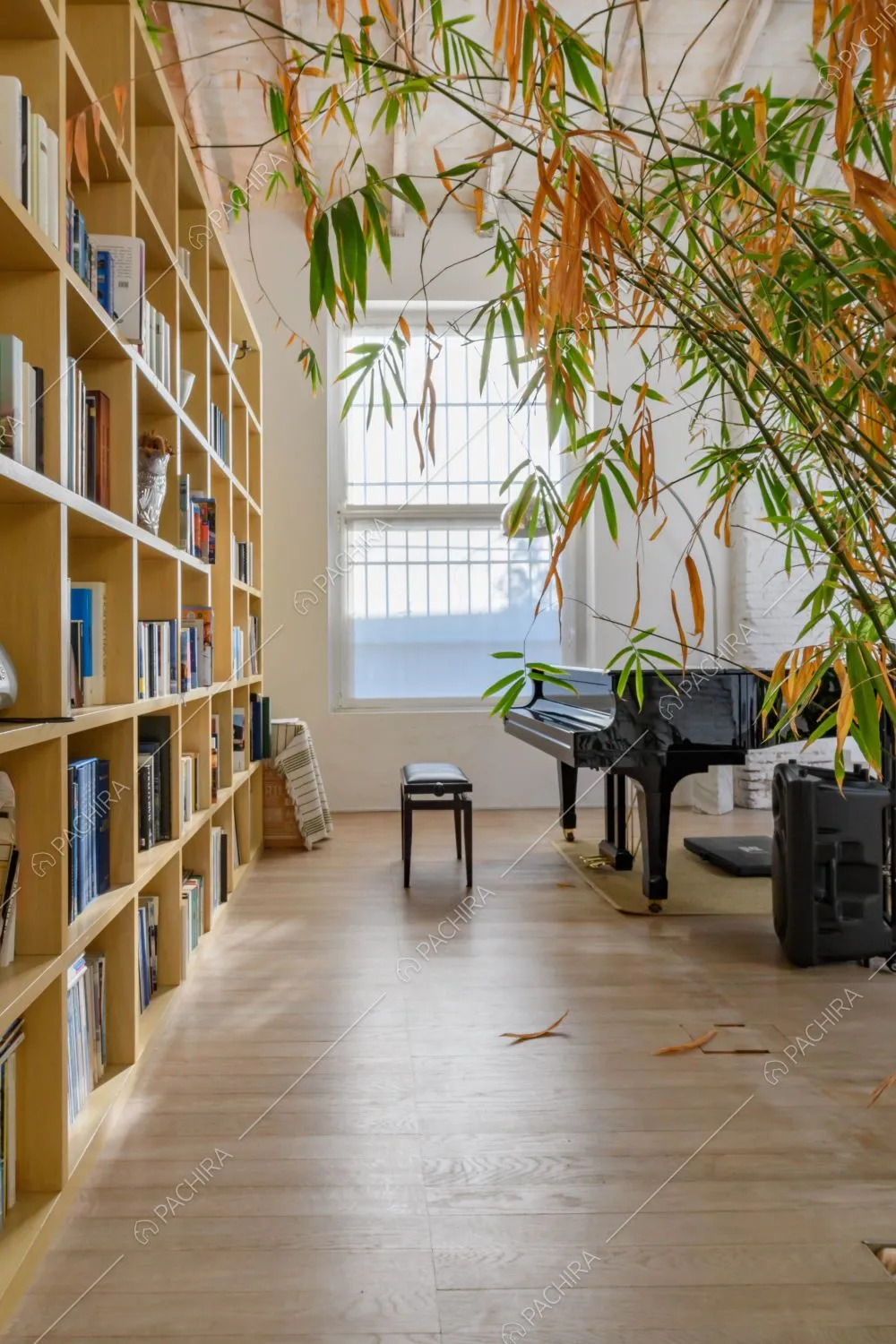 Pavimento in parquet nella zona living con libreria gialla a muro e pianoforte nero