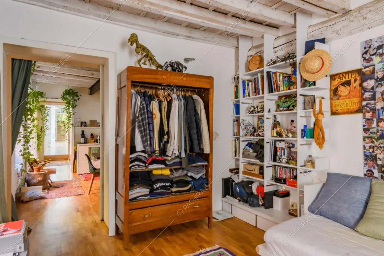 Camera da letto con pavimento in parquet, pareti bianche e vista sulla cucina