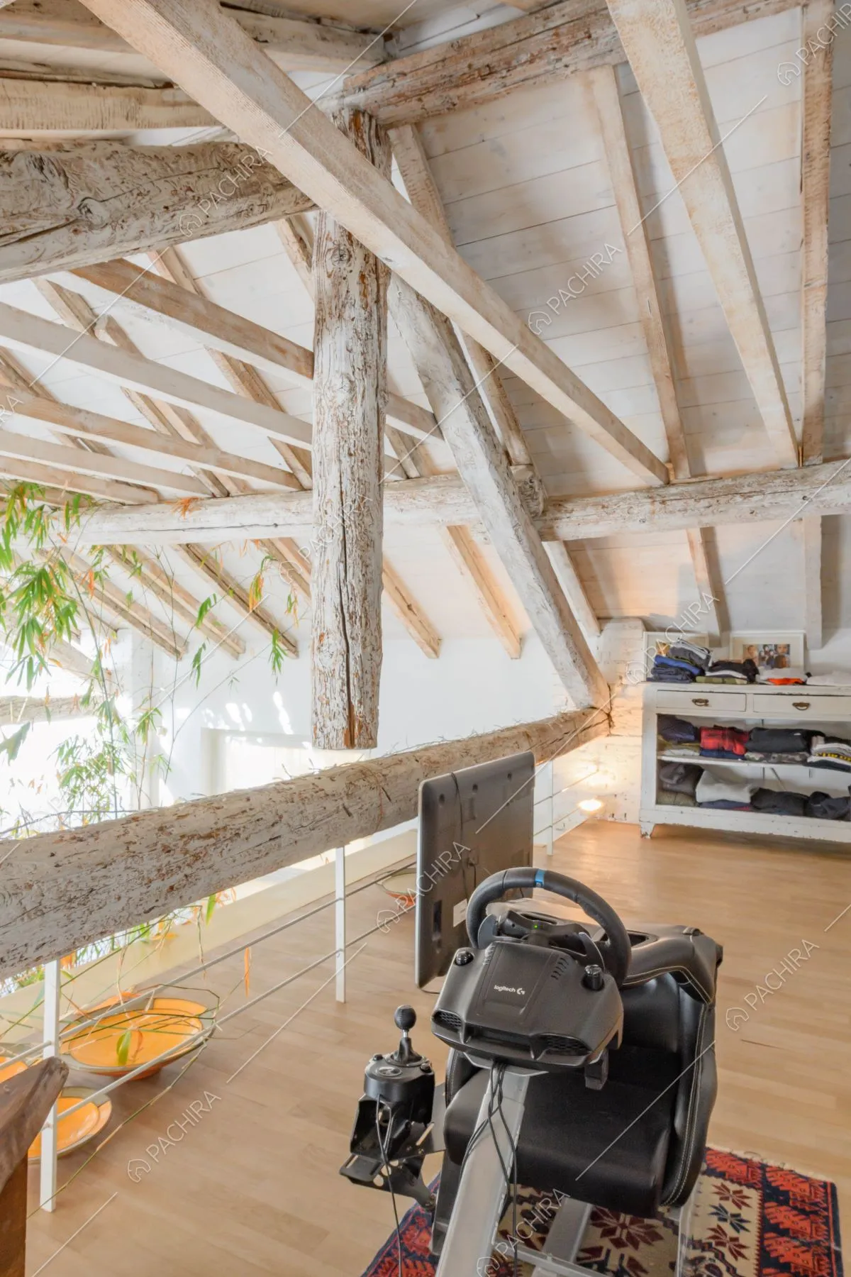 Camera da letto sul soppalco con travi in legno a vista sul soffitto e pavimento in parquet
