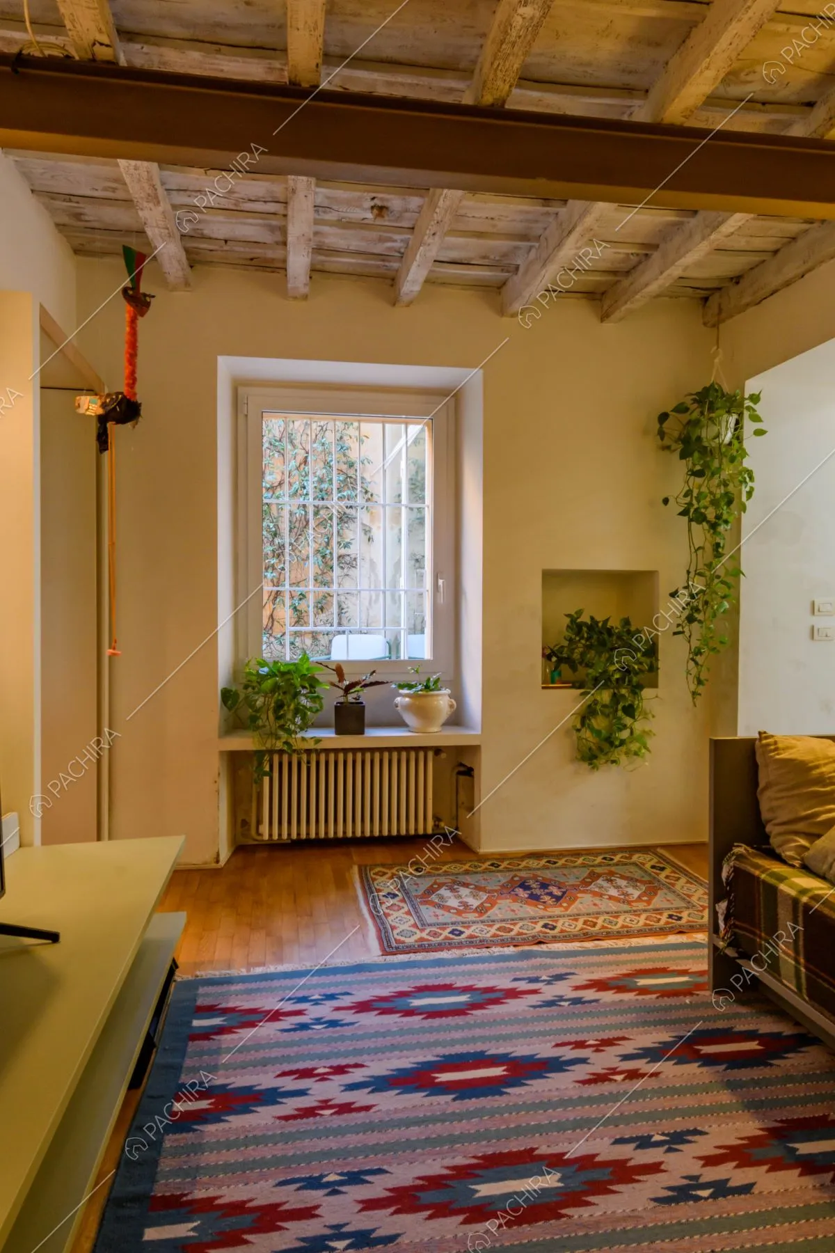Sala con pavimento in parquet, travi a vista e vetrata
