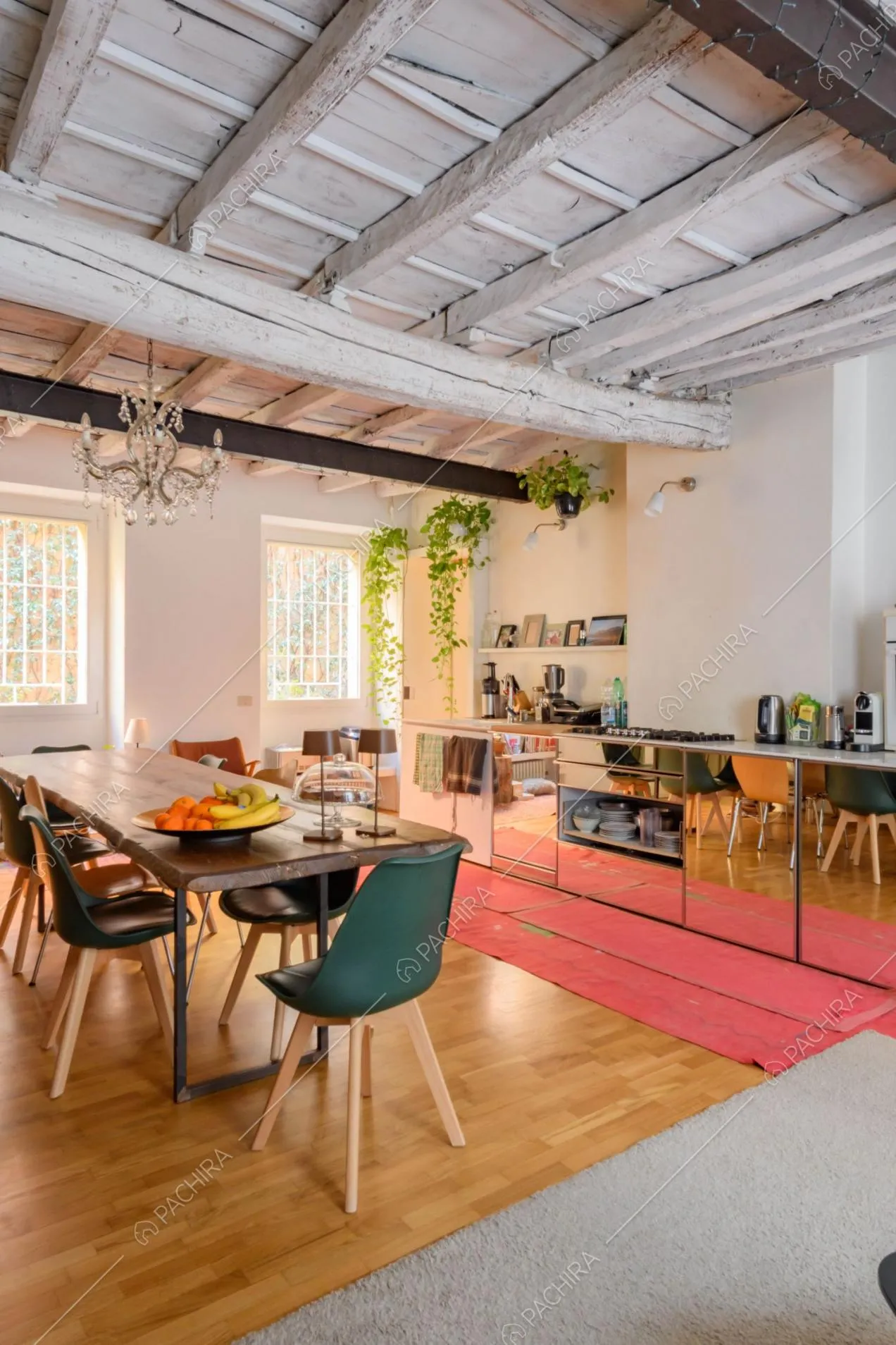 Tavolo da pranzo, lampadario e cucina a parete con fornelli a gas