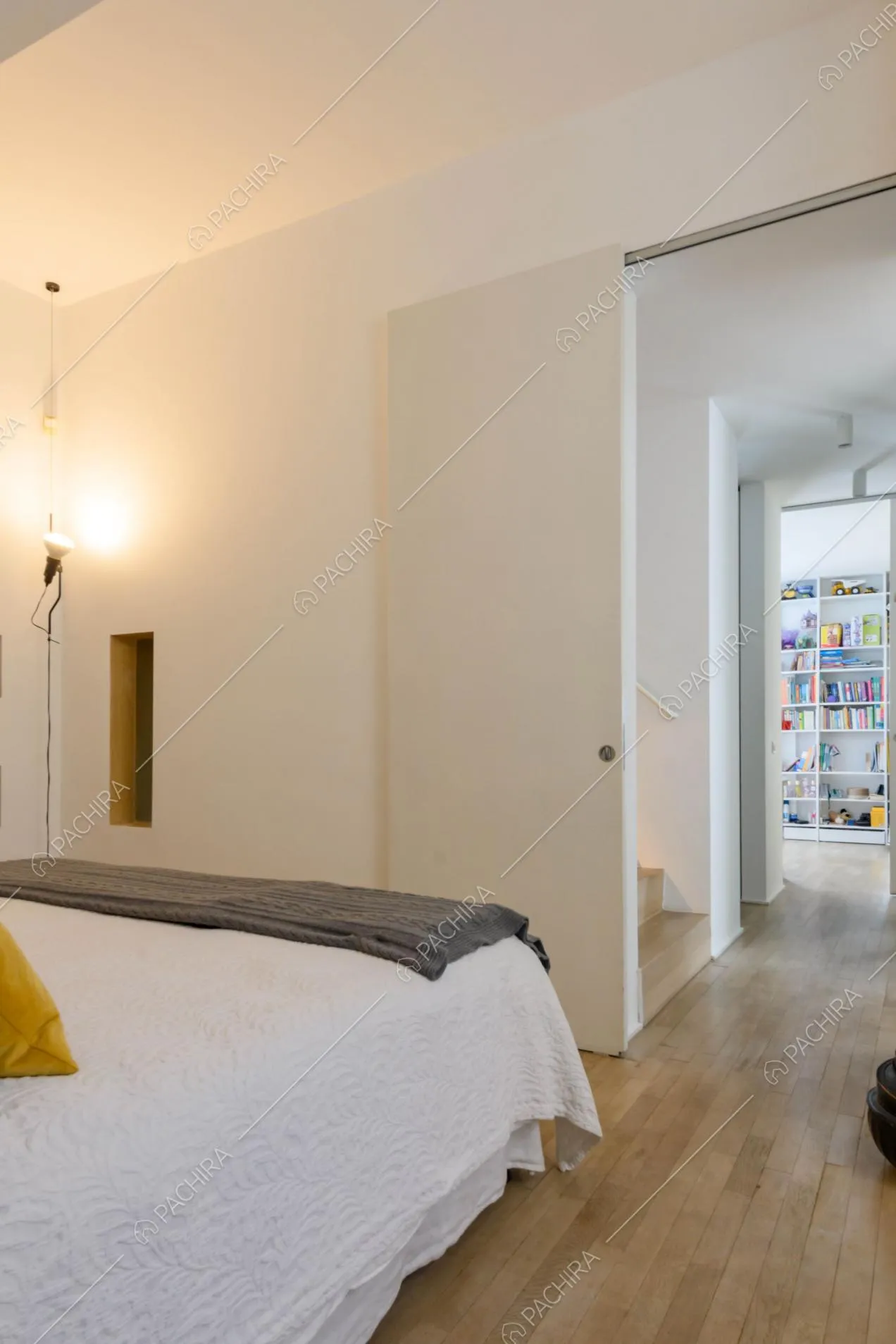 Camera da letto matrimoniale con pareti bianche, porta scorrevole e pavimento in parquet