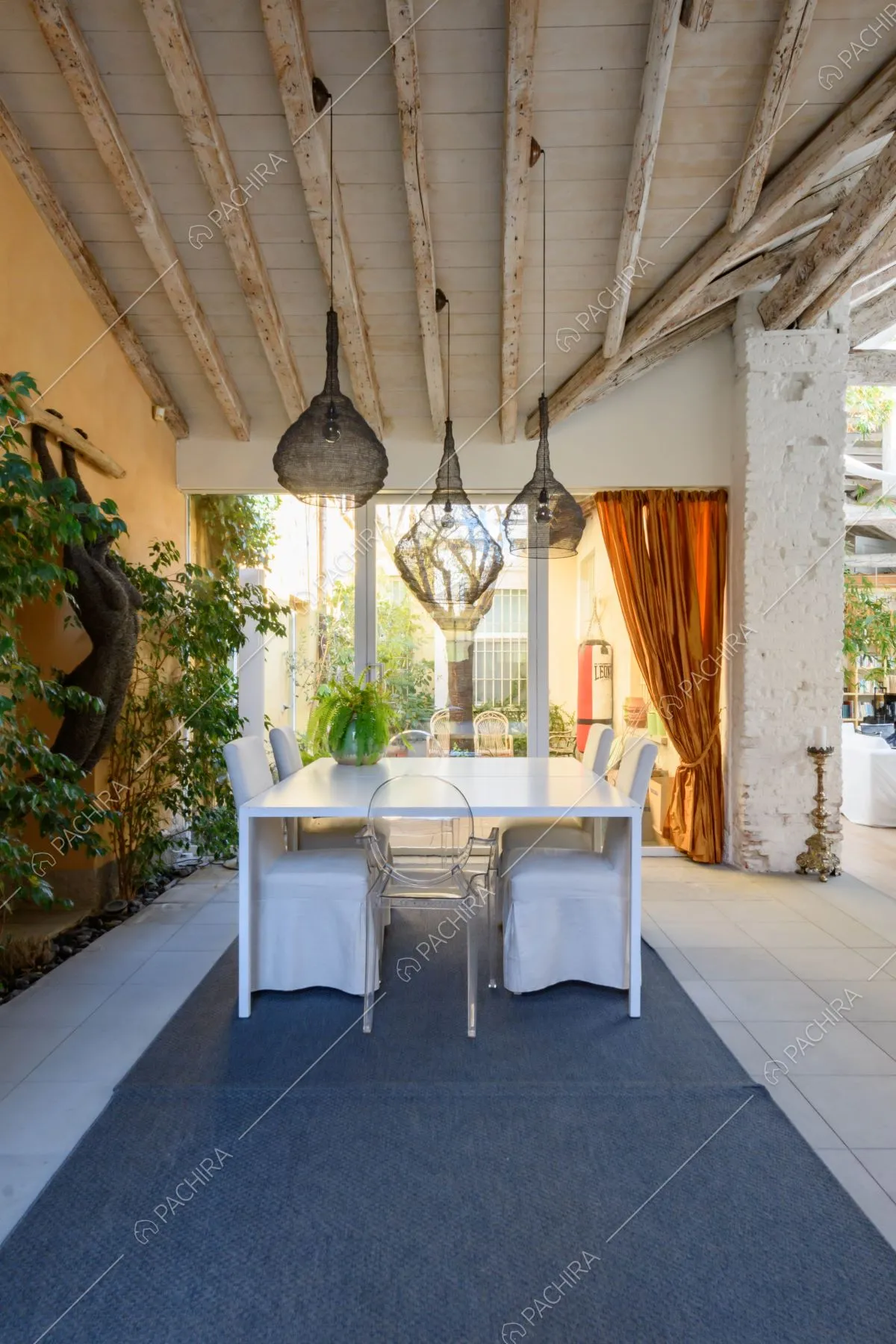 Tavolo da pranzo e sedie bianche nella veranda con pavimento in piastrelle