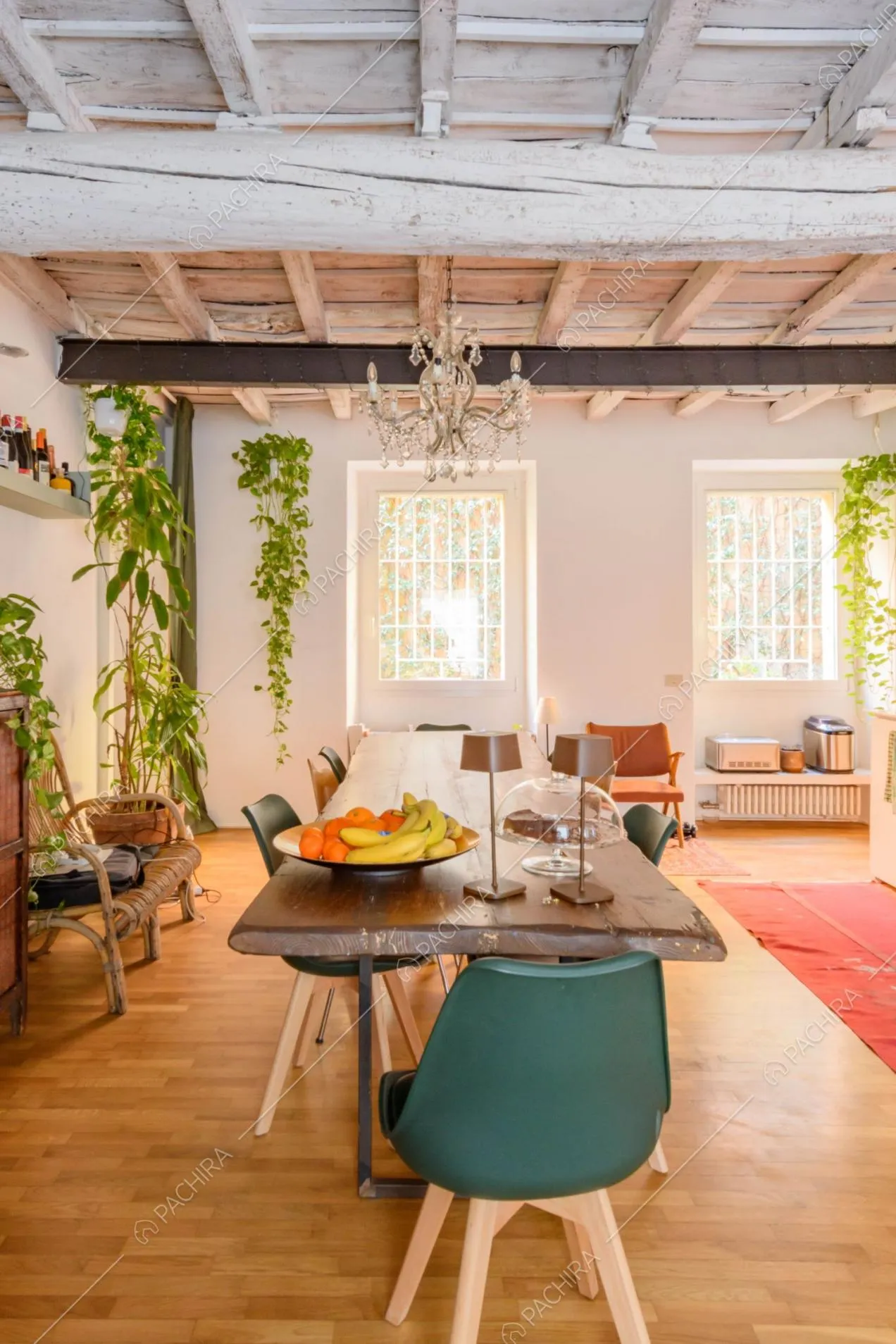 Tavolo da pranzo in legno grezzo nella luminosa cucina con pavimento in parquet