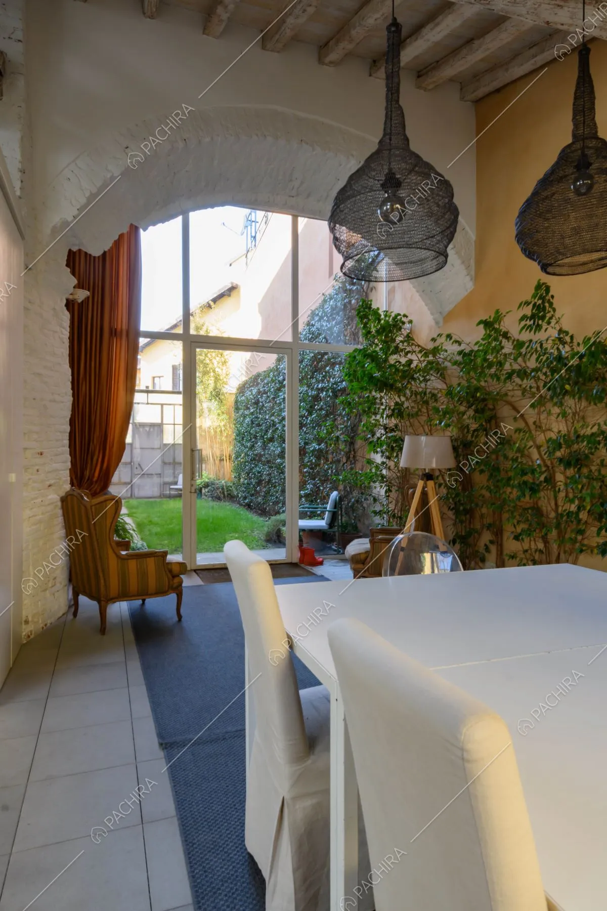 Veranda con vista sul giardino tramite la vetrata inserita in un arco a tutto sesto