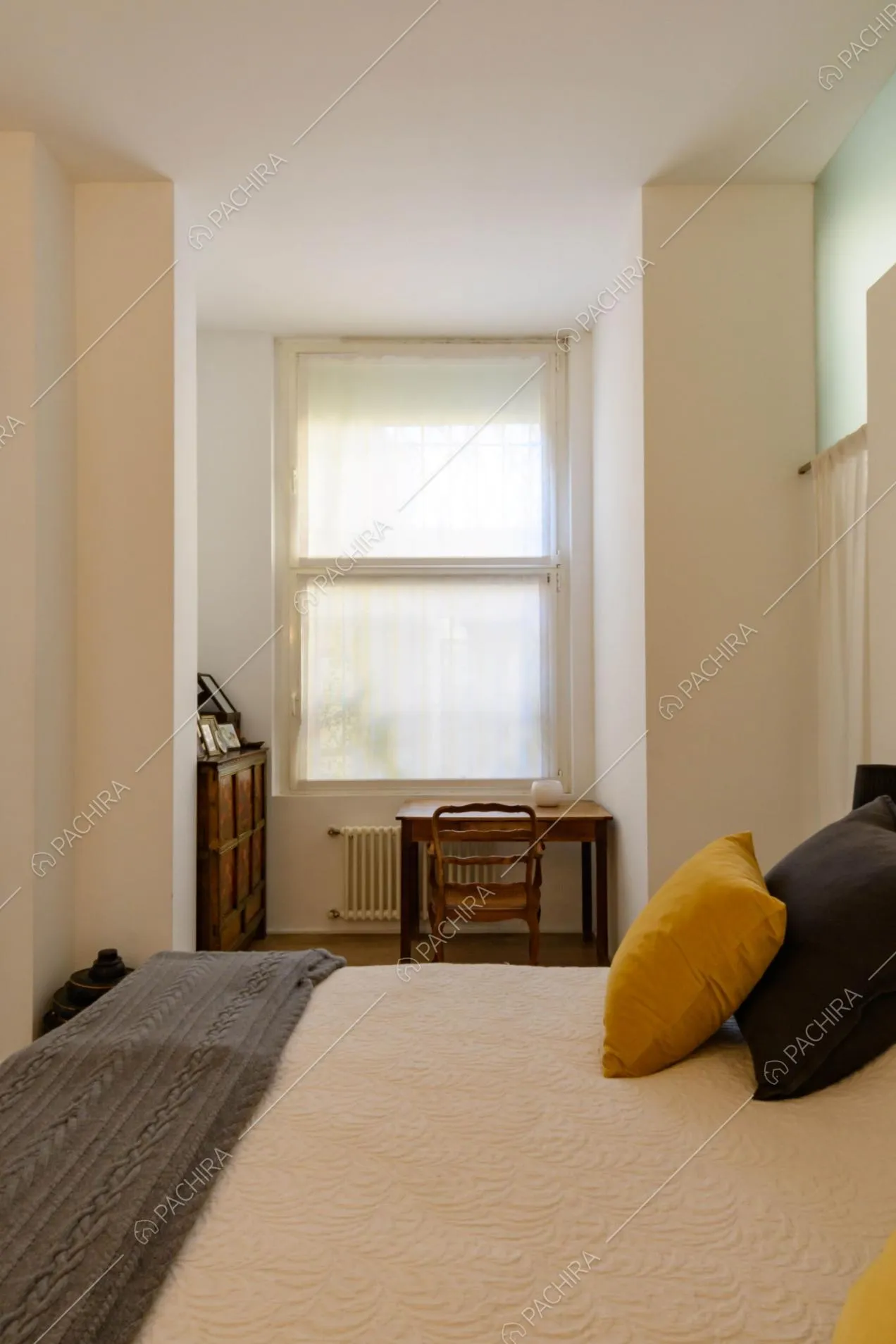 Camera da letto matrimoniale con pareti bianche e scrivania