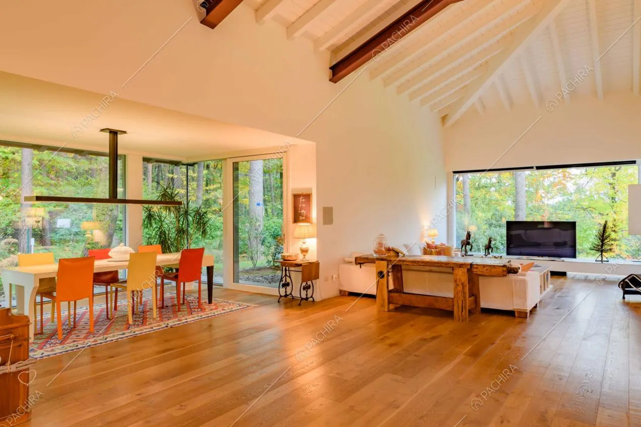 Zona living con pavimento in parquet, pareti bianche e soffitto con travi in legno a vista