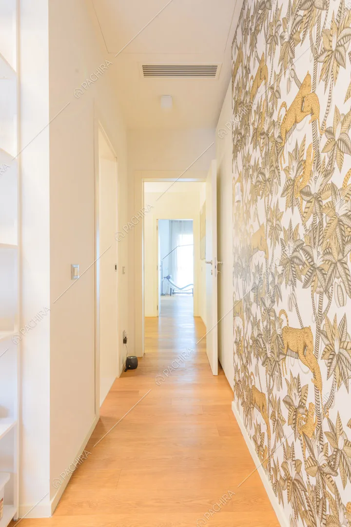 Lungo corridoio con pavimento in parquet e carta da parati a fantasia tropicale