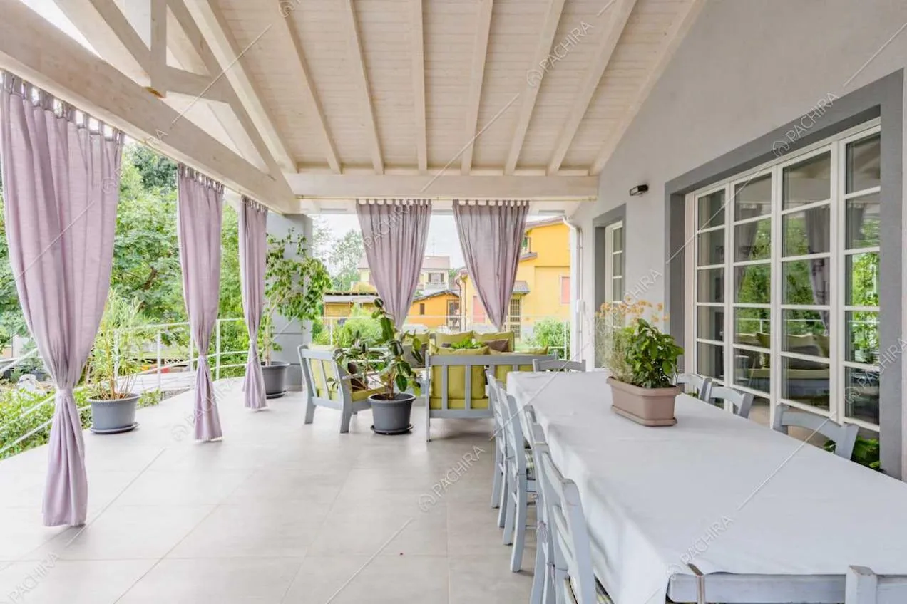 Grande veranda con soffitto in travi in legno a vista e grande tavolo da pranzo