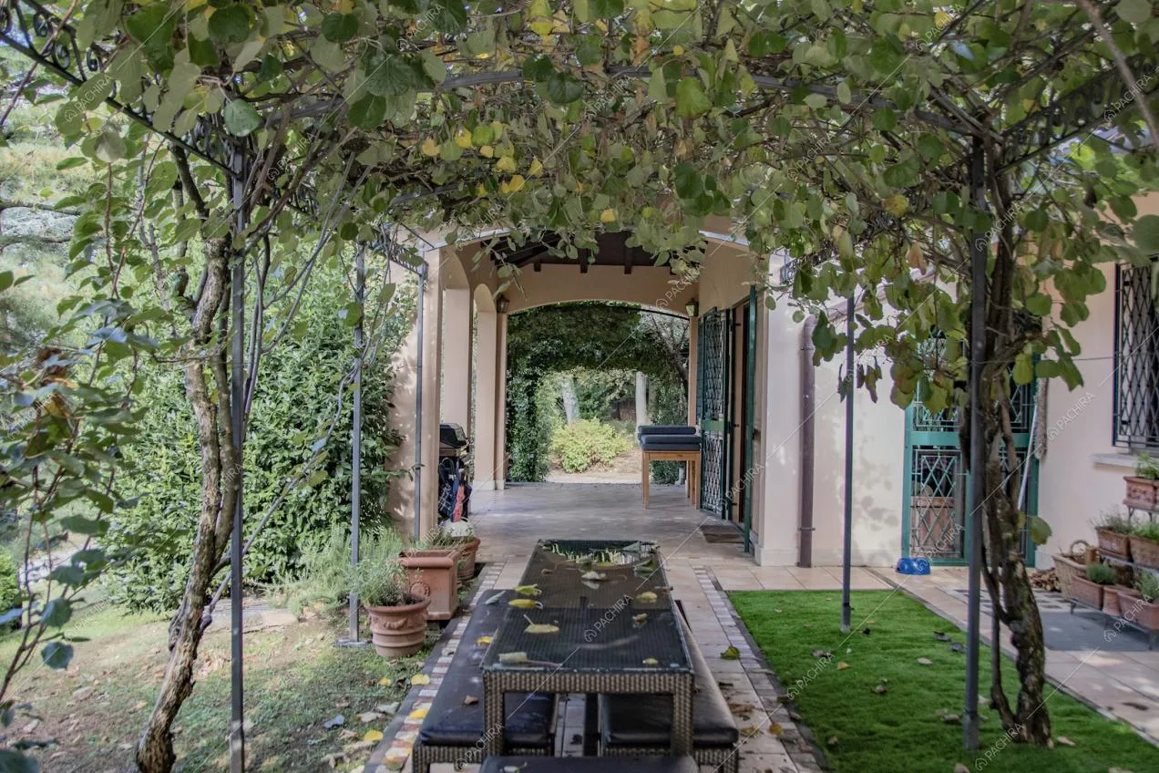 Sotto al lungo arco da giardino con rampicanti ecco un tavolo da pranzo con panche