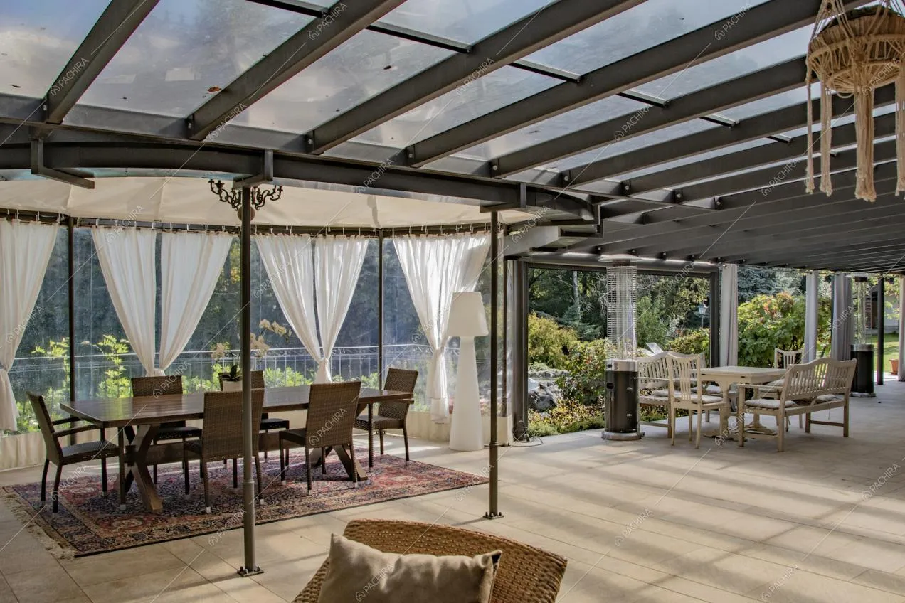 Tavoli da pranzo nella luminosa veranda con pareti e soffitto in vetro