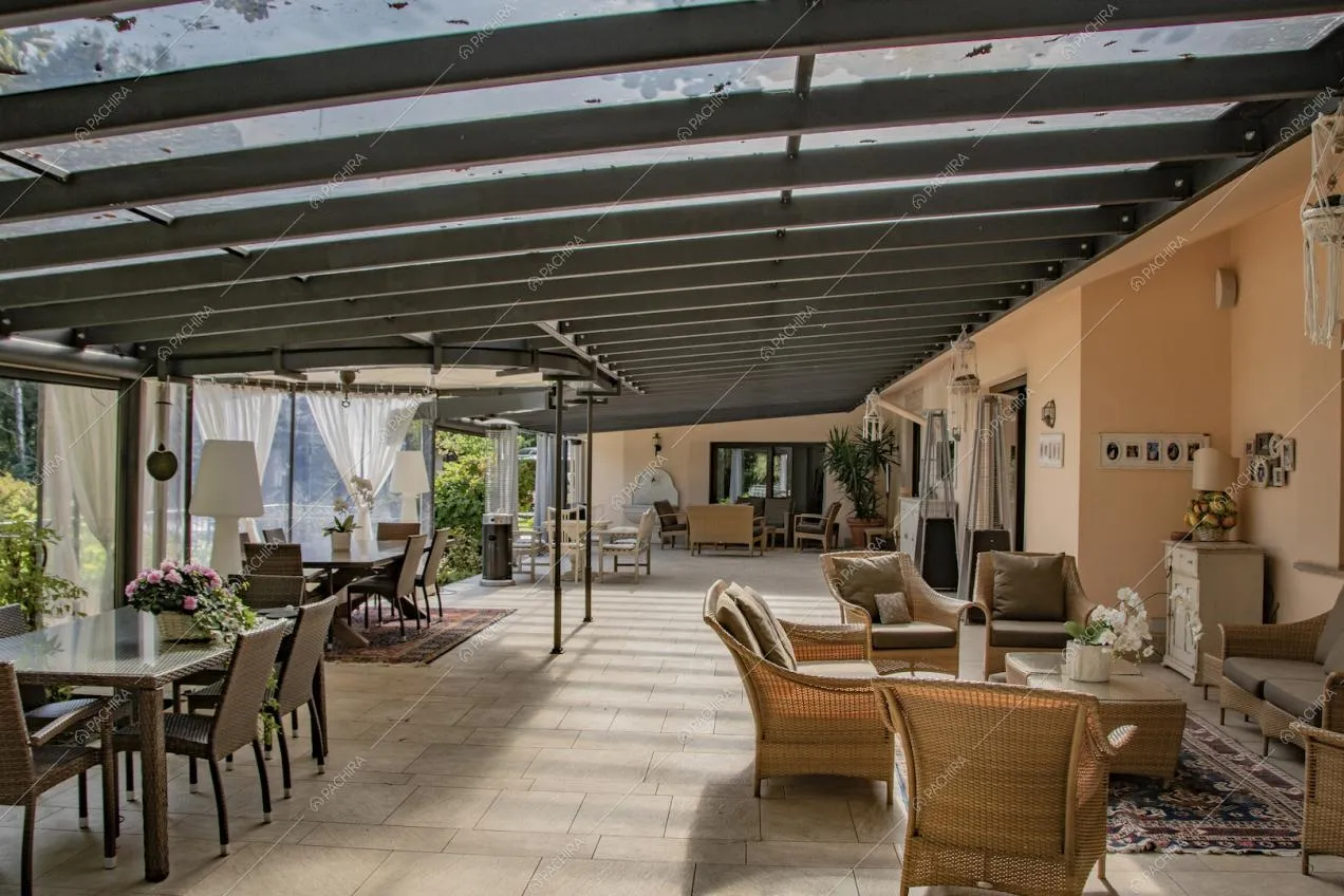 Ampia veranda con tavoli da pranzo, divanetti e poltrone