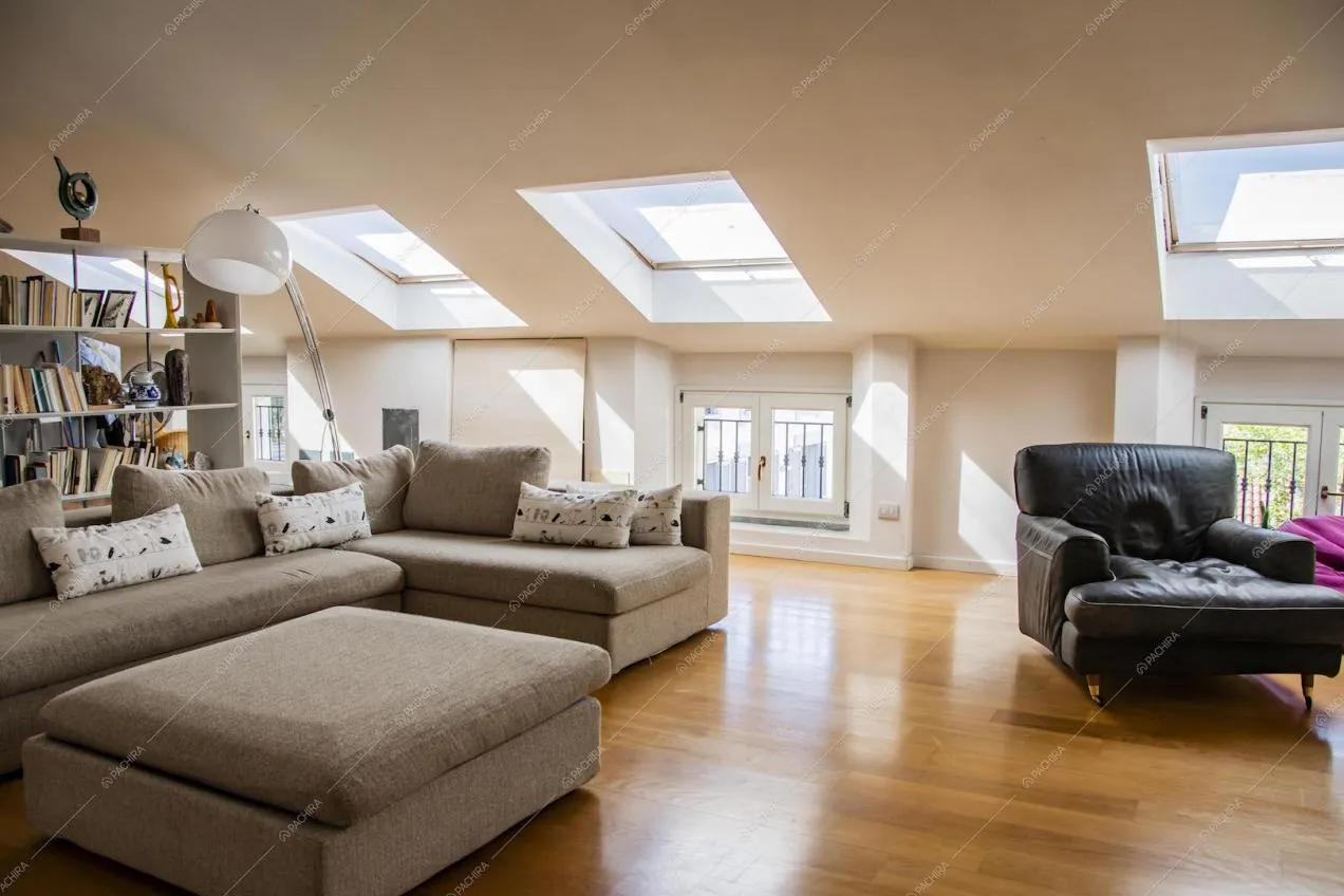 Lucernari nella splendida mansarda con divano angolare e soffitto bianco