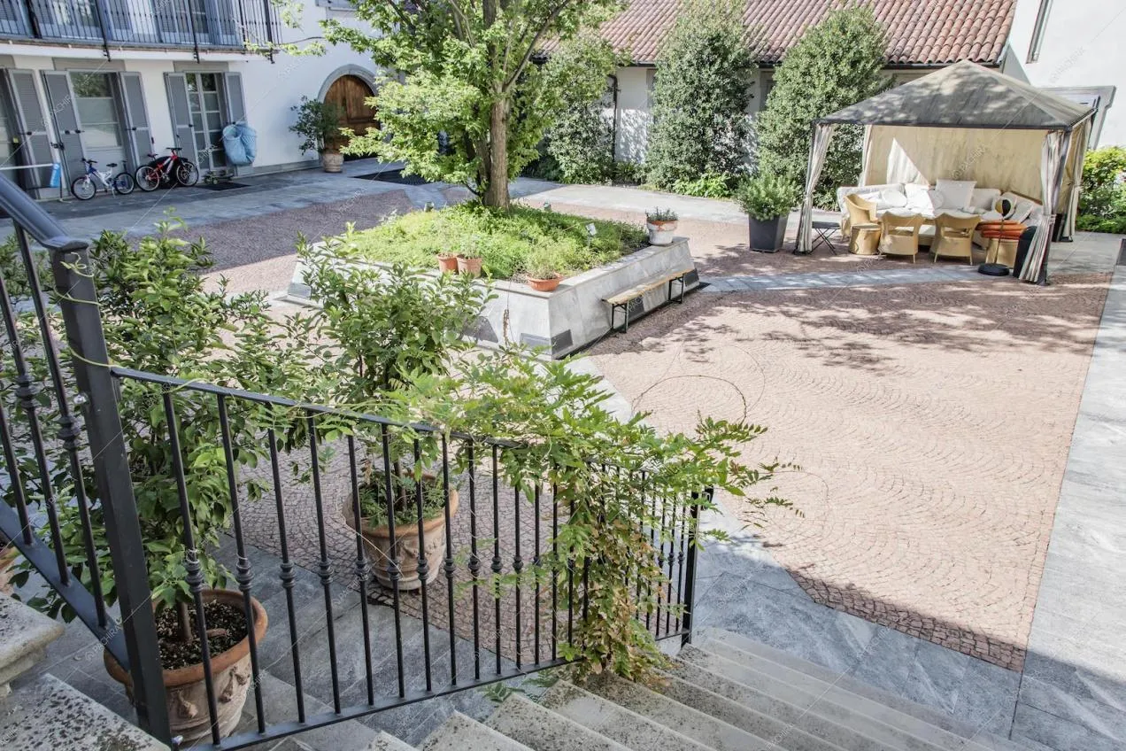 Dalla scalinata vista sul cortile interno con pavimento in ciottoli e gazebo