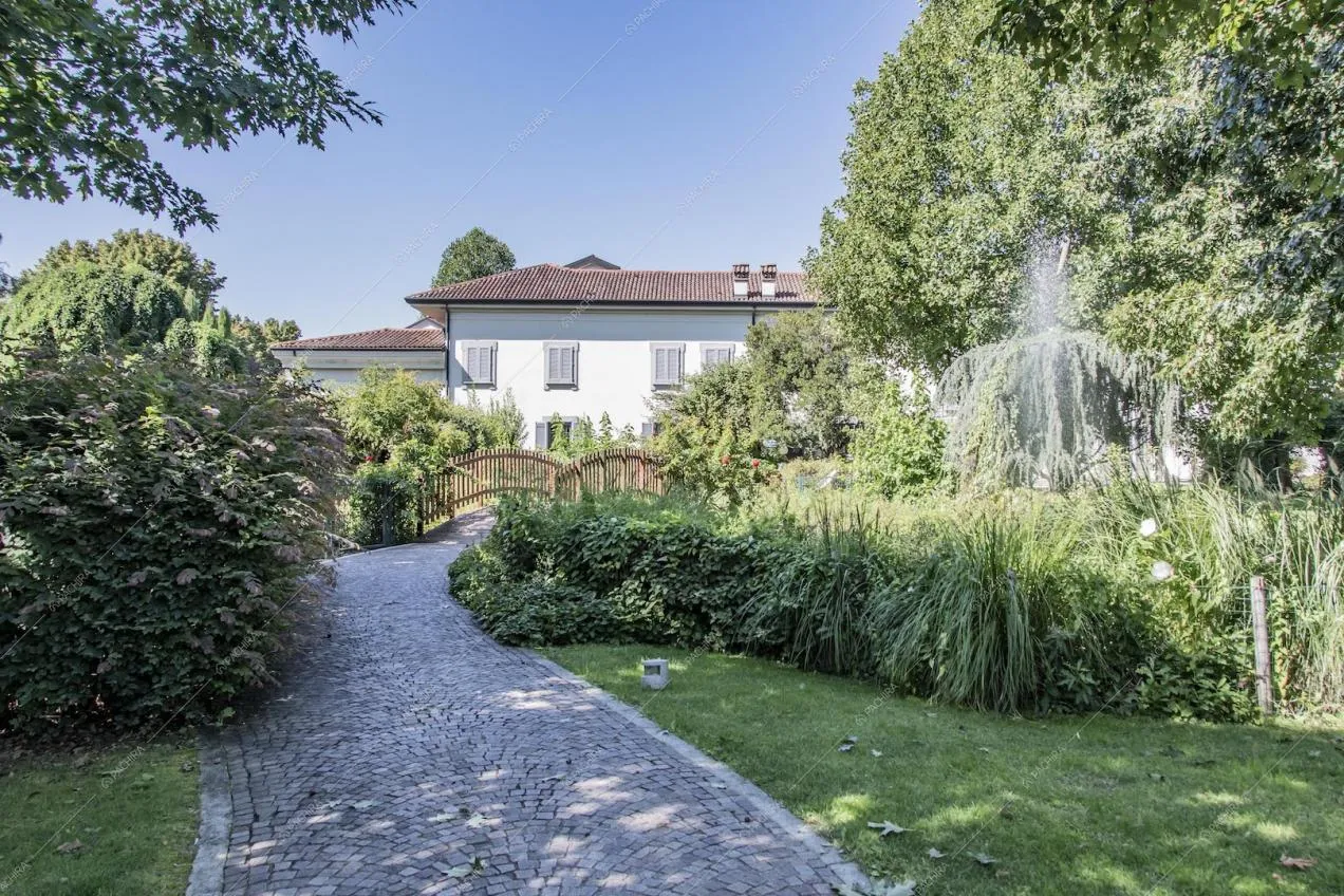 Vialetto del giardino con scorcio sul piccolo ponte e sugli esterni della villa