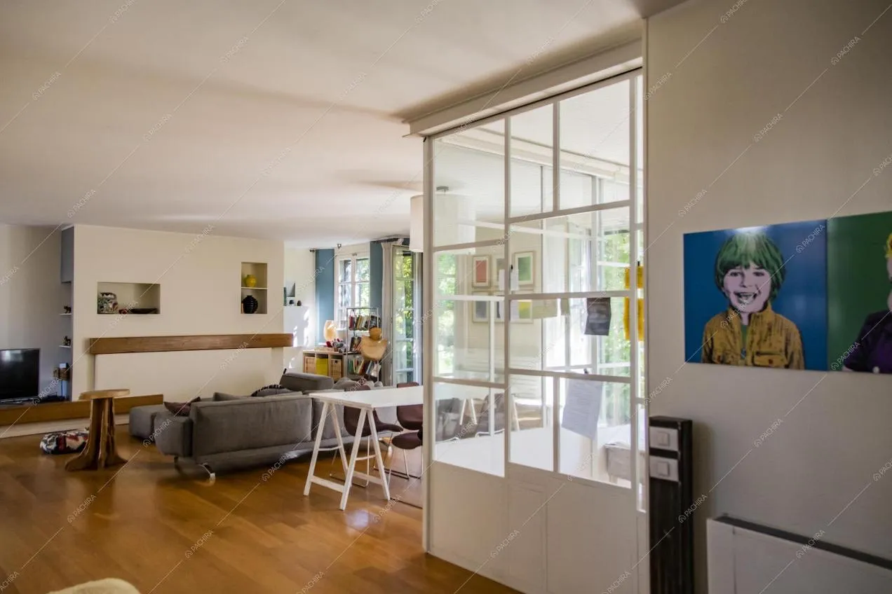 Salotto con pavimento in parquet, pareti bianche e vetrate industriali