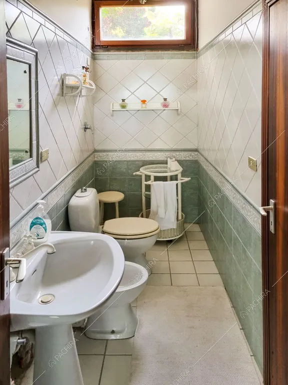 Bagno con piastrelle bianche e verdi sulle pareti e sul pavimento