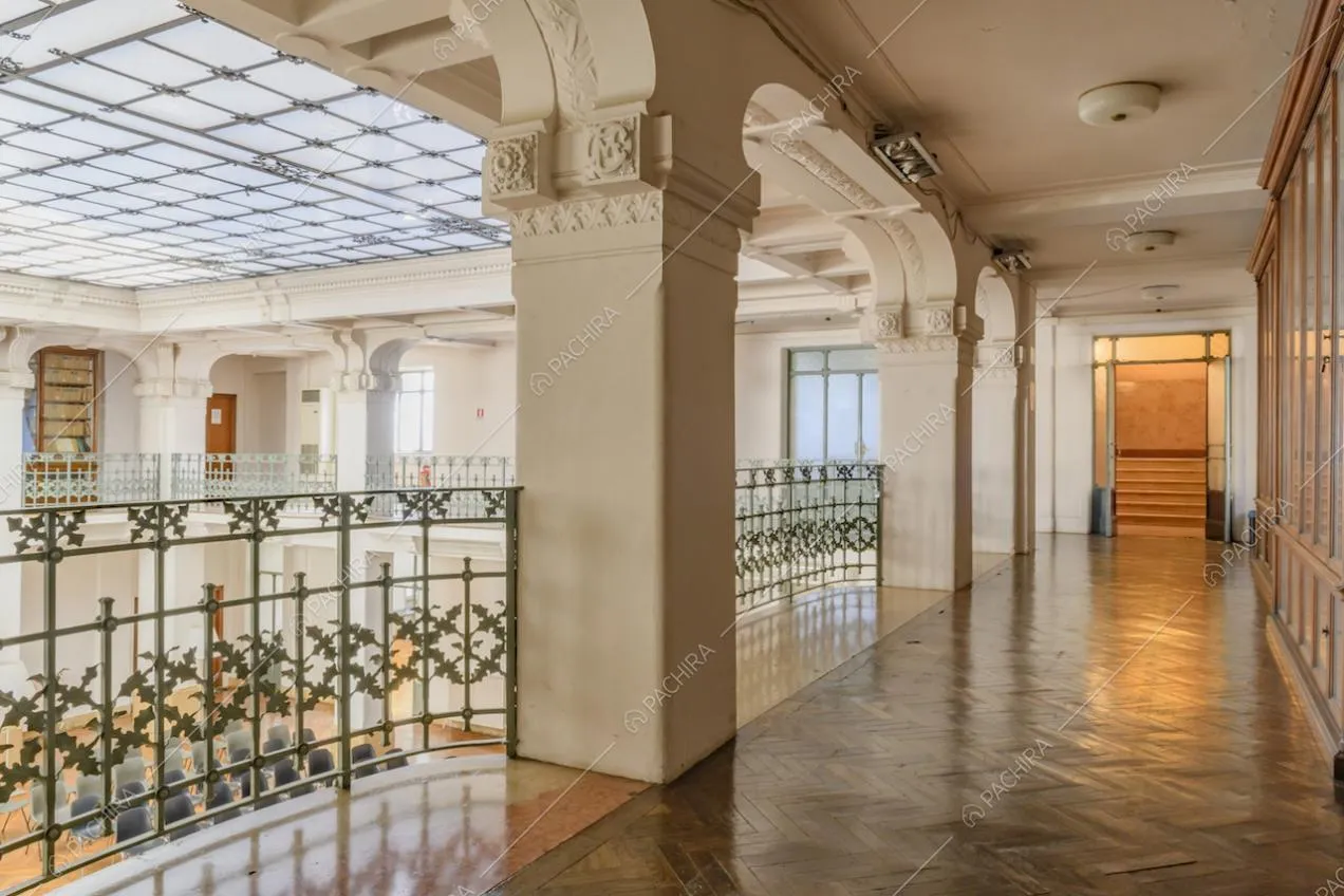 Balconata con pavimento in parquet a spina di pesce e in marmo, colonne con boiserie e vista sulle scale