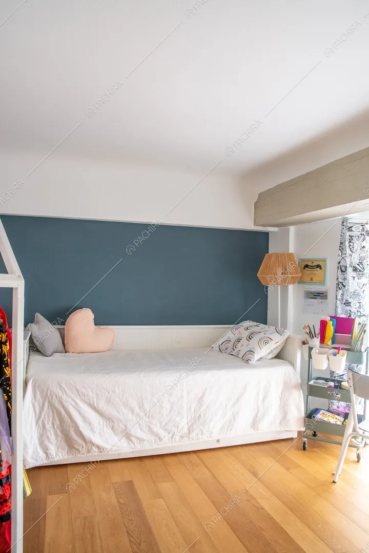 Camera da letto con parete blu, soffitto bianco, letto singolo e pavimento in parquet