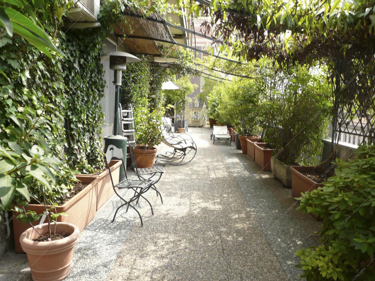 Terrazza con pavimento in ciottolato, pergola e piante