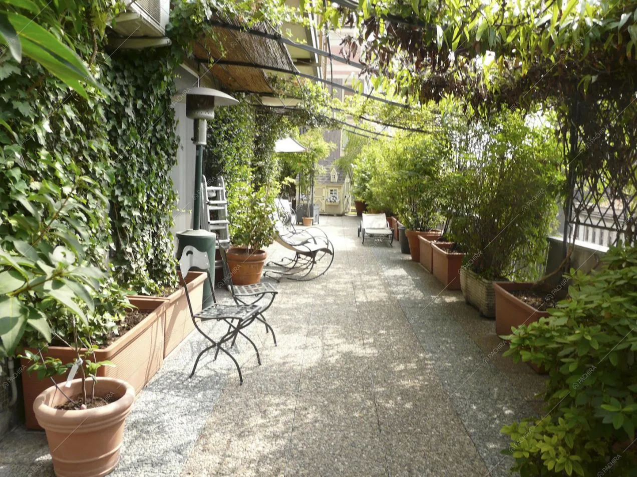 Terrazza con pavimento in ciottolato, pergola e piante